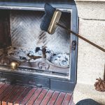  man cleans the furnace of fire with a spatula and brush on a long handle